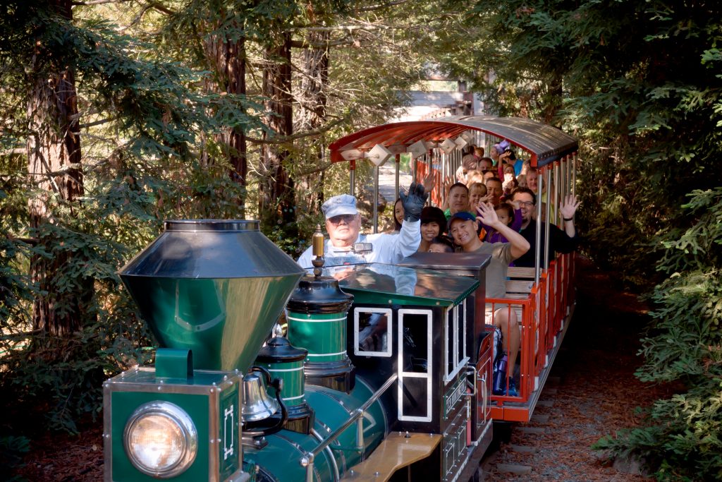 People riding and waving on the train at Gilroy Gardens