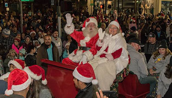 Santa Claus with Mrs. Claus on their sleigh around many people