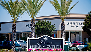 Gilroy Premium Outlets sign near palm trees
