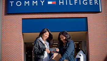 2 women looking in their shopping bag in front of Tommy Hilfiger Outlet