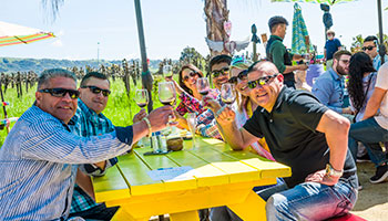 Group of people wine tasting and sitting on a yellow bench