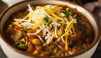 Bowl of chili with white and yellow cheese on top