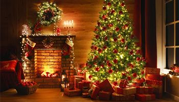 Christmas tree lit up near a fireplace