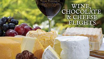 Grapes, red wine in a glass, cheese and chocolate on a table