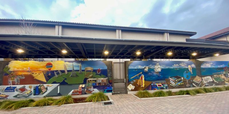 Gilroy Library mural with books and ocean scenes with pirate ships and a sunset