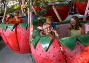 There are kids and a dad riding strawberries on the Strawberry Sundae ride at Gilroy Gardens