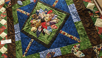 Quilt with a green diamond in the middle with floral pattern