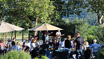 People sitting and drinking wine while enjoying music played by a band