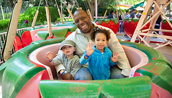 Man smiling while on a strawberry ride with his children
