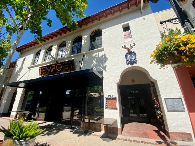 Front of Tempo Kitchen & Bar, a historical stucco building with an Elk & shield over an archway from its Elks Lodge days
