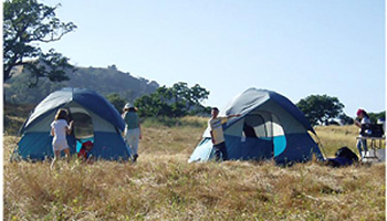 Two blue camping tents with people around them in Gilroy