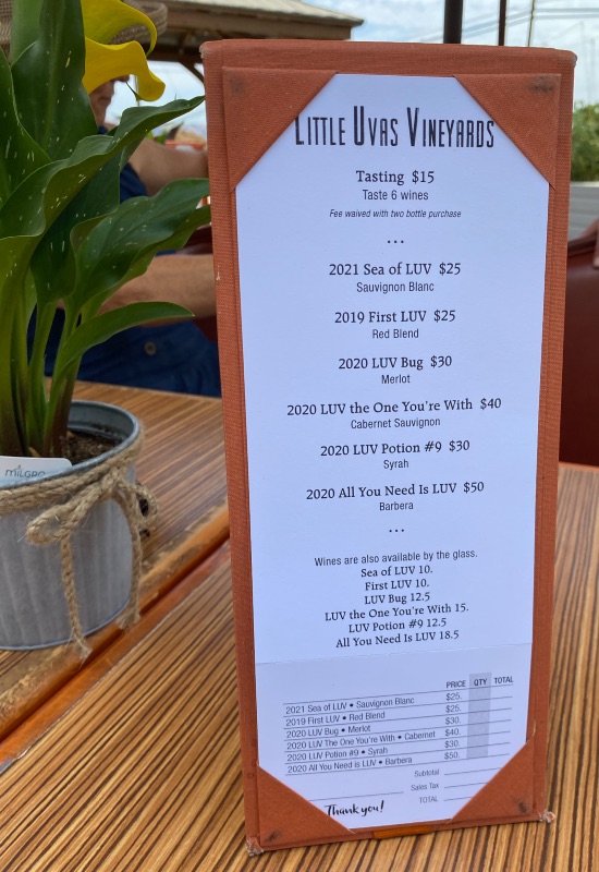 a tasting menu for a winery next to a plant on a table
