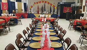 Gilroy Veterans Hall with tables, brown chairs and red glod star balloons