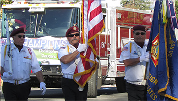 Veterans in front of a fire truck holding flags