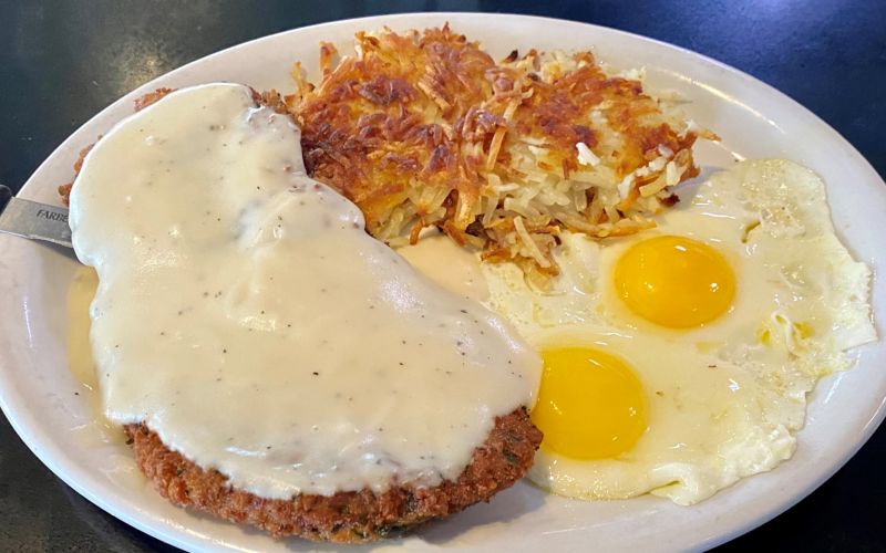 a chicken fried steak with hash browns and fried eggs