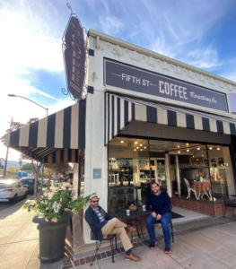 two men seated with coffee cups in front of Fifth Street Coffee Roasting company