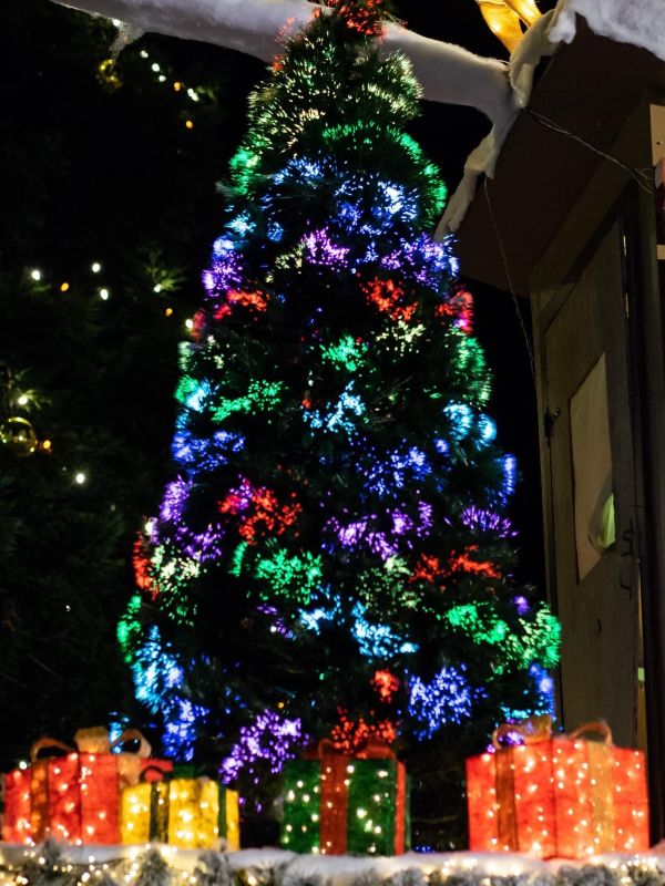 a Christmas tree with colorful lights and lit up presents underneath