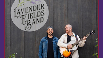 Lavender Fields band standing next to a wall while holding a guitar