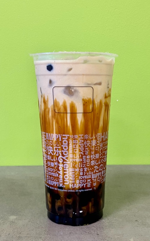 a black tea with milk in a clear cup with bright green background