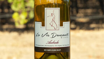 Bottle of La Vie Dansante Aubade wine with a vineyard in the background