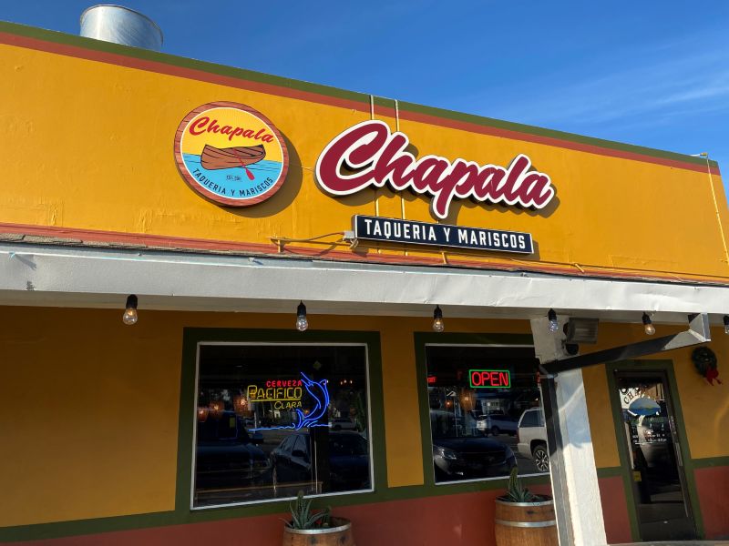 the exterior of a restaurant with bright golden paint on top and red paint below with a big sign in red letters