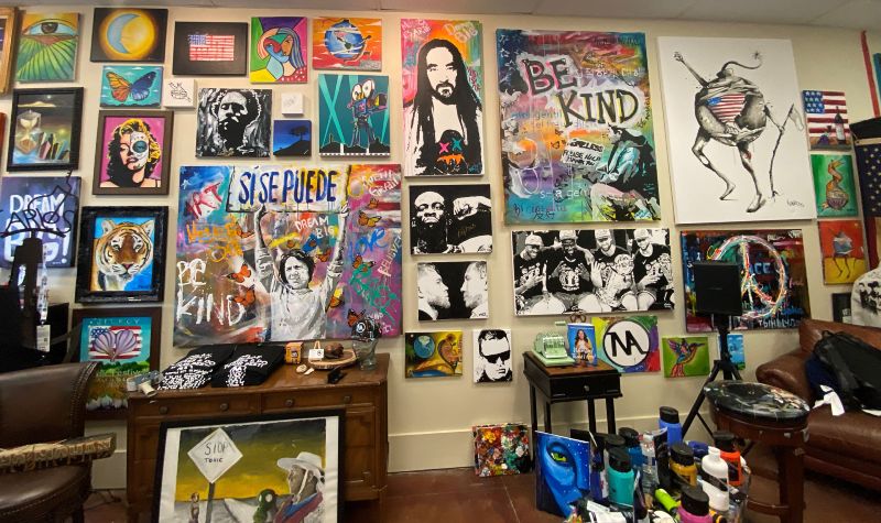 an artist's studio wall covered in colorful paintings