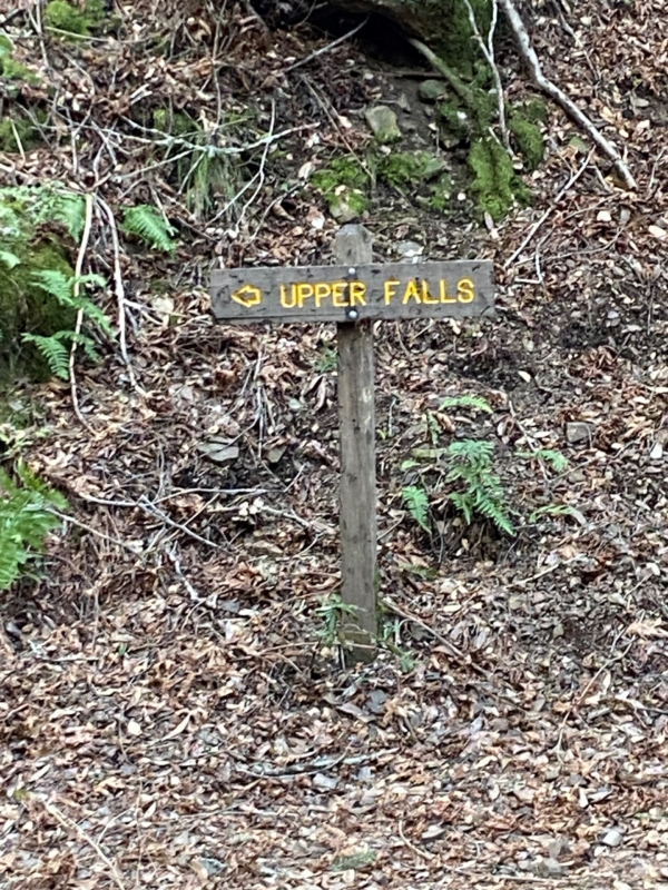a wooden sign pointing to the Upper Falls waterfall