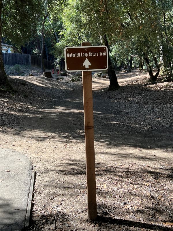 a sign in the dirt pointing to the Waterfall Loop Nature Trail