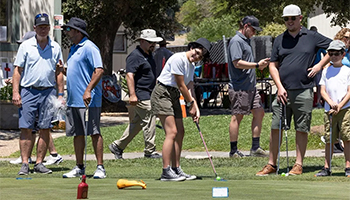 Adults and children golfing on a green golf course