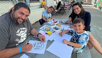 Family smiling and drawing while enjoying the Third Friday Art Walk