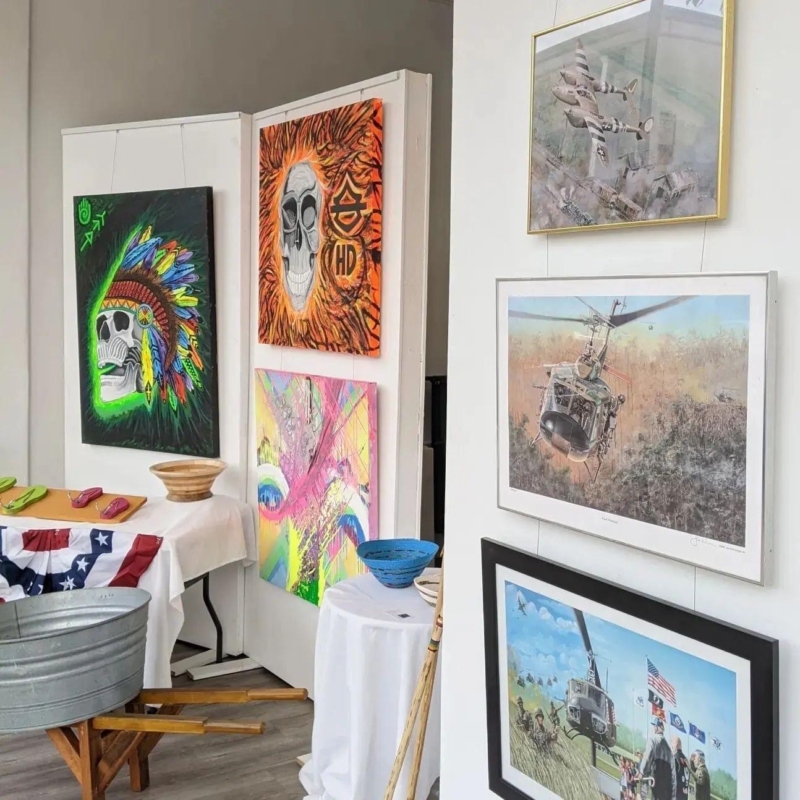 some paintings and drawings on display with scenes of skulls and war aircraft