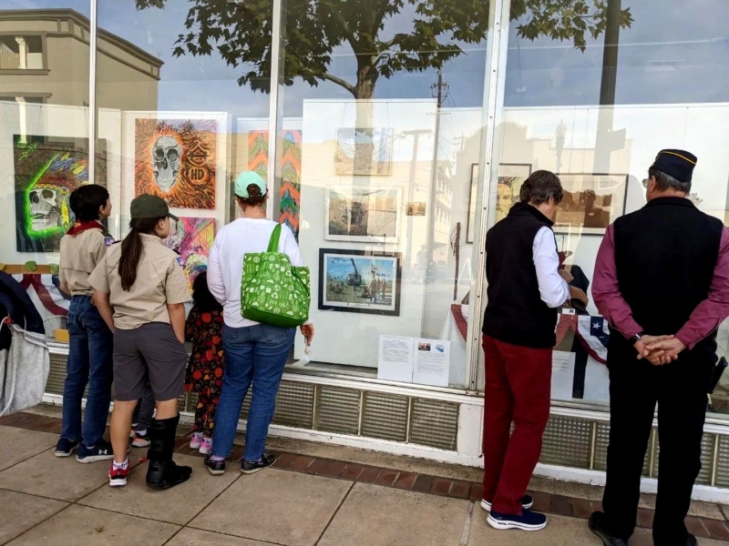 a group of people looks through the windows of an art studio at art on display