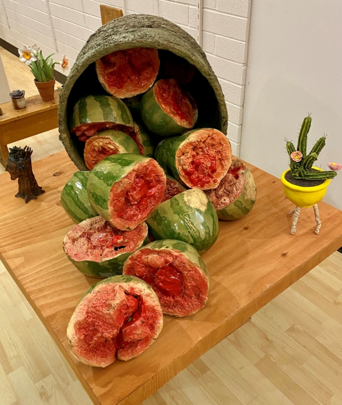 a sculpture of watermelon halves spilling out of an overturned barrel