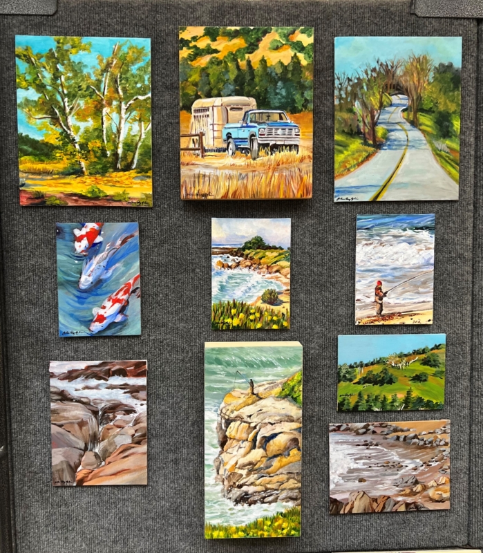 several colorful outdoor scenes on canvases are displayed on a gray wall