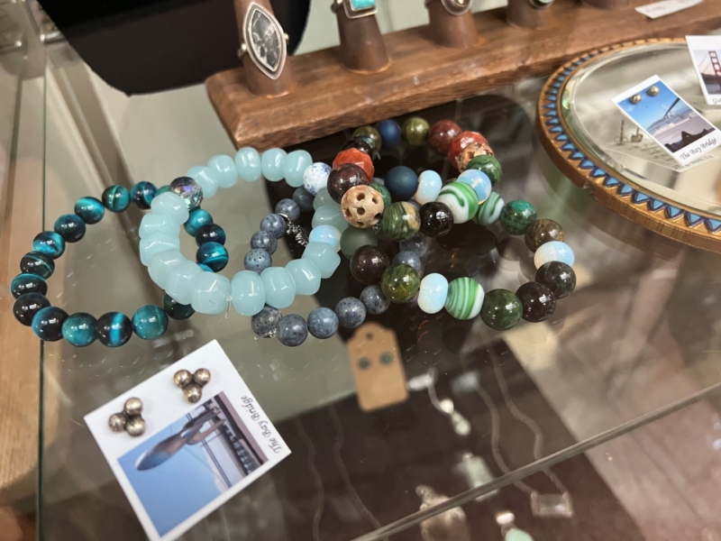 bracelets made from colorful stones are on a glass shelf