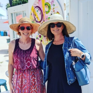 two ladies in sun hats smile outside of an art studio