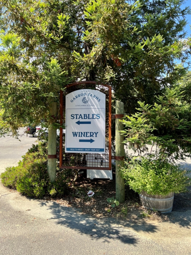 a sign pointing to stables and a winery