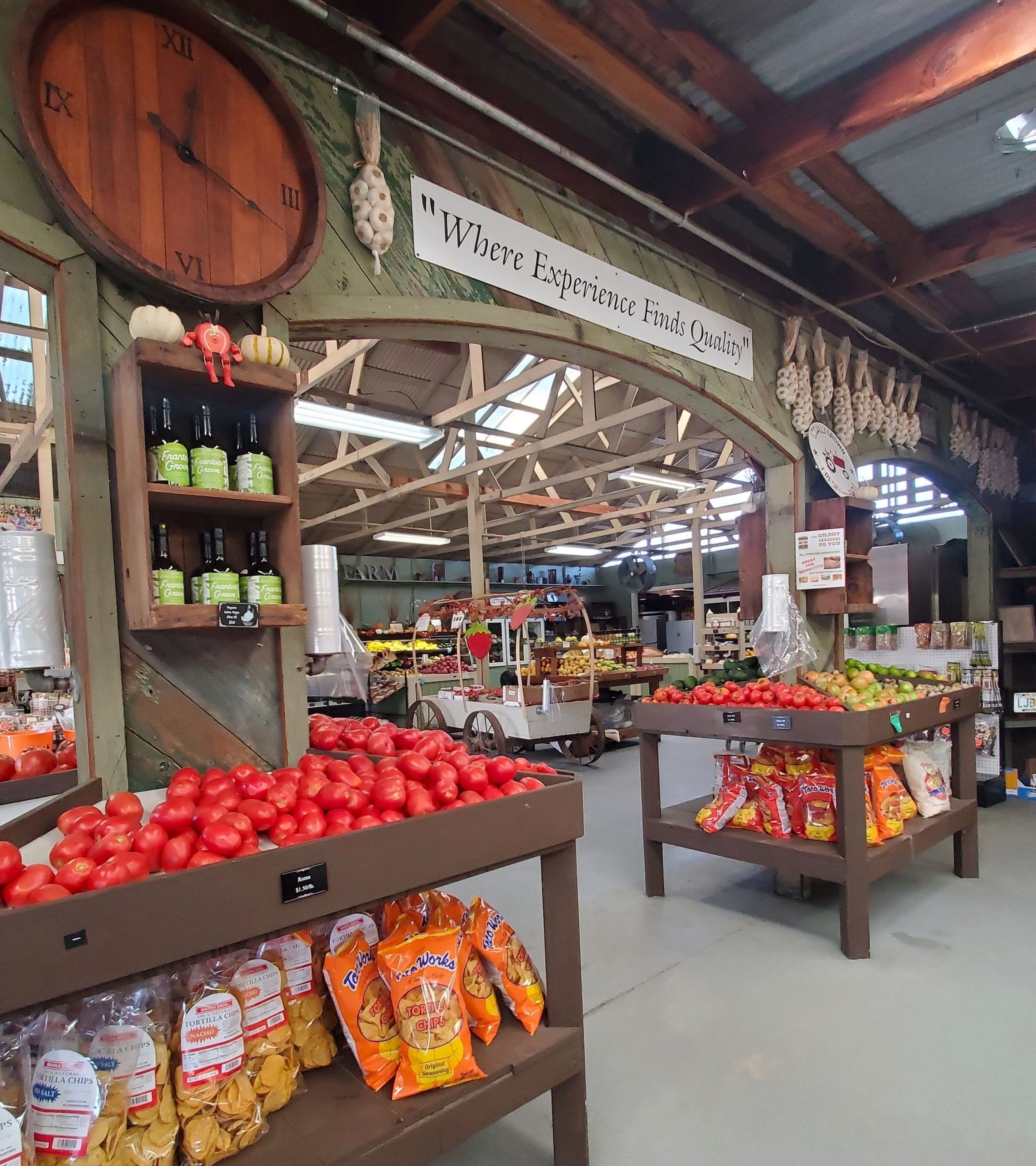 Inside the LJB farmhouse store, showing fresh tomatoes apples, olive oils, garlic braids, and bagged chips.