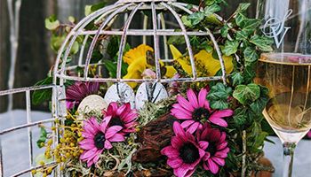 White bird cage decorated in bright pink, yellow ans white spring flowers.